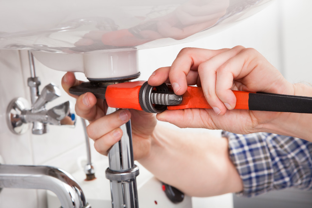 A plumber fixing a bathroom sink with a pipe wrench