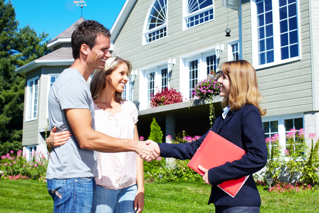 A couple talking to a real estate agent outside the house