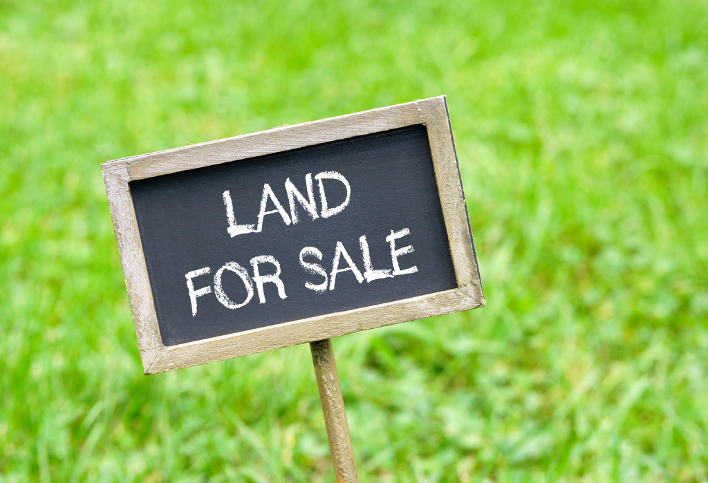 Land for sale sign on green grass.