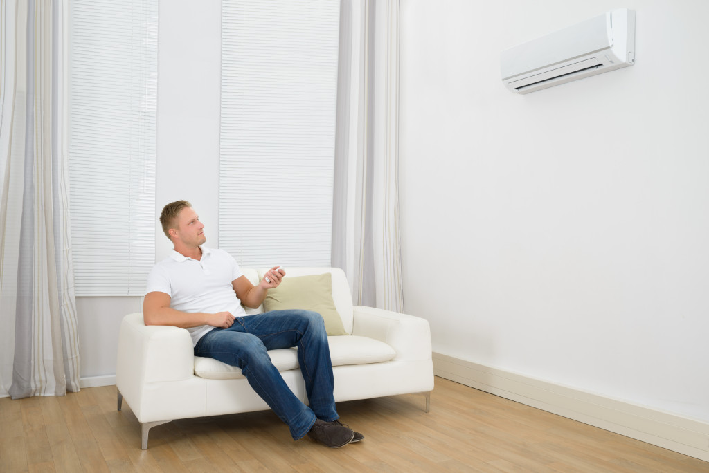 A man sitting on a sofa in front of an air conditioner